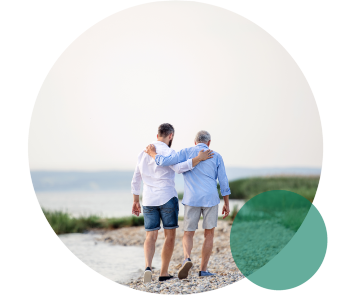 Das Bild zeigt Vater und Sohn am Strand spazieren Das Bild zeigt Vater und Sohn am Strand spazieren