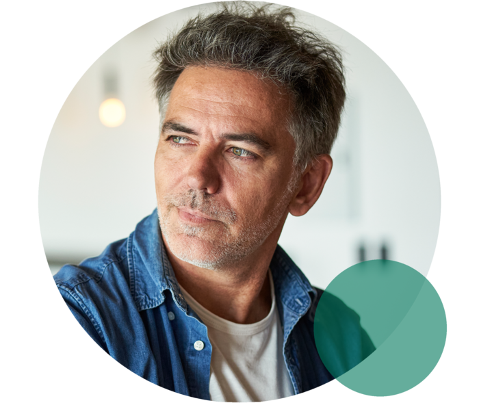 Lipoprotein(a): Das Risiko kennen Mann mit ergrautem Haar und Dreitagebart blickt nach links.