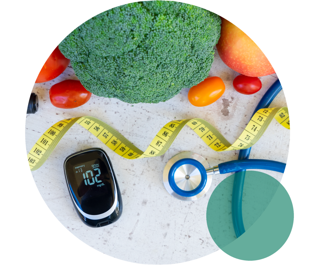 Begleiterkrankung metabolisches Syndrom Ein Blutzuckermessgerät liegt neben einem Stethoskop, einem Maßband sowie Brokkoli, Tomaten und einem Apfel.