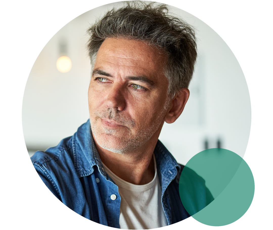 Lipoprotein(a): Das Risiko kennen Mann mit ergrautem Haar und Dreitagebart blickt nach links.