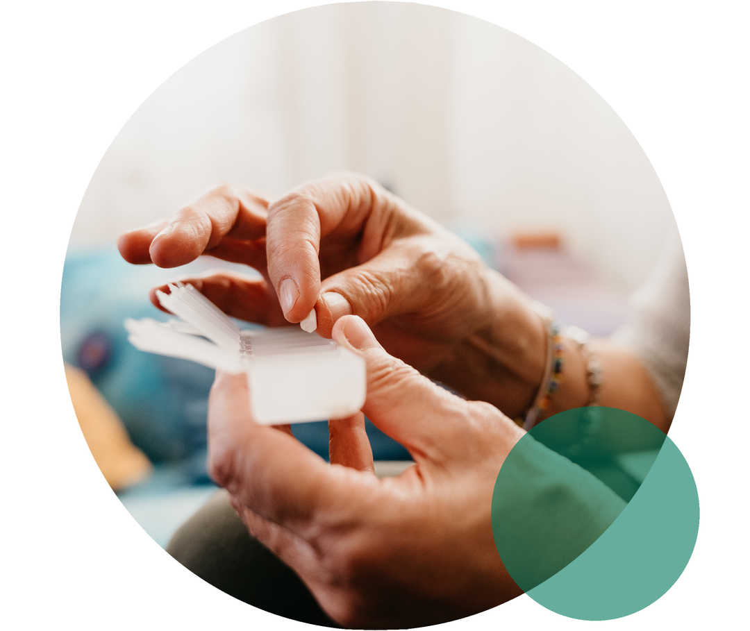 Hypercholesterinämie: Therapietreue Seniorin hält eine Pillendose in der Hand, in die sie Medikamente einsortiert.
